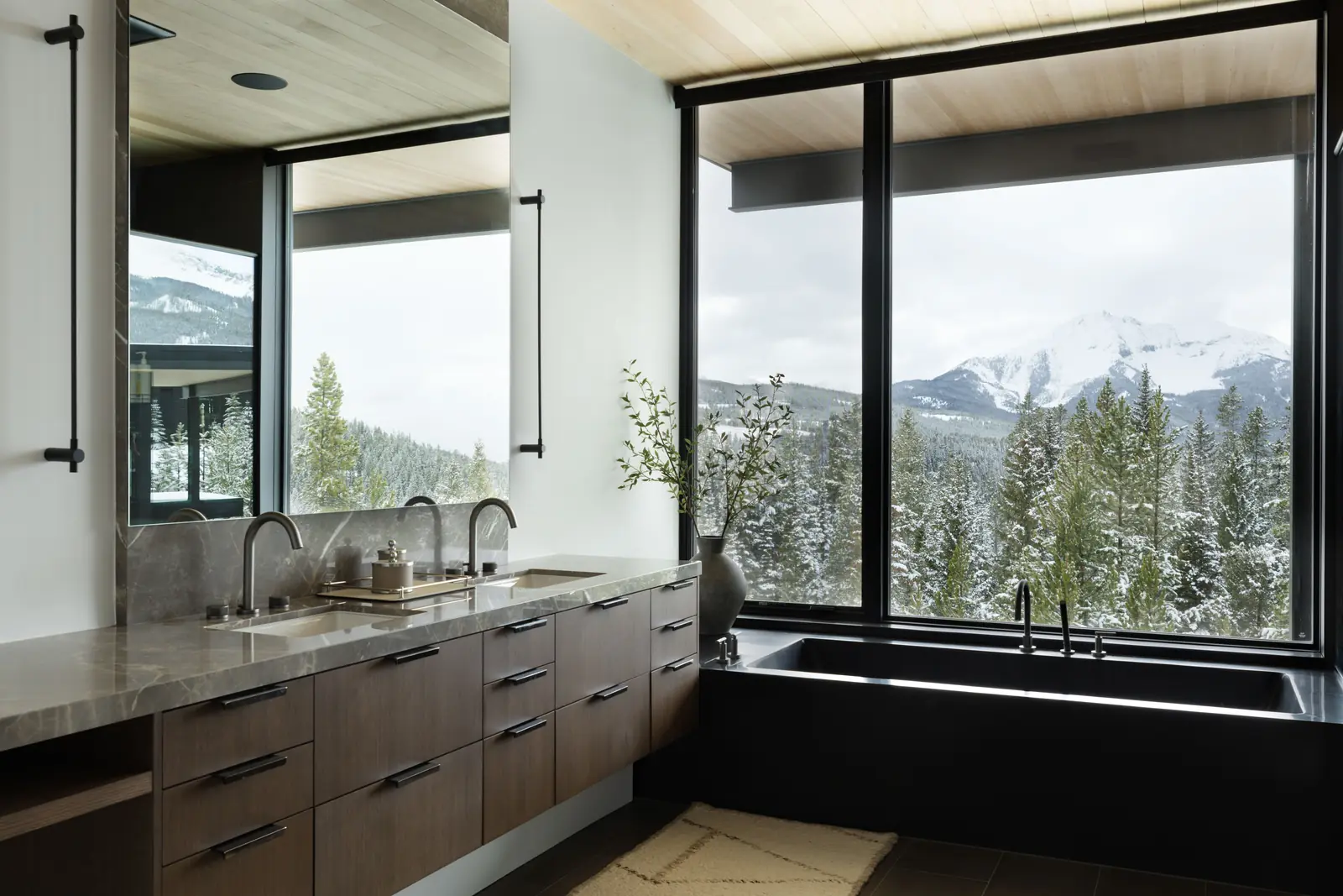 Primary bath with a long walnut vanity and a soaking tub beneath the mountain view