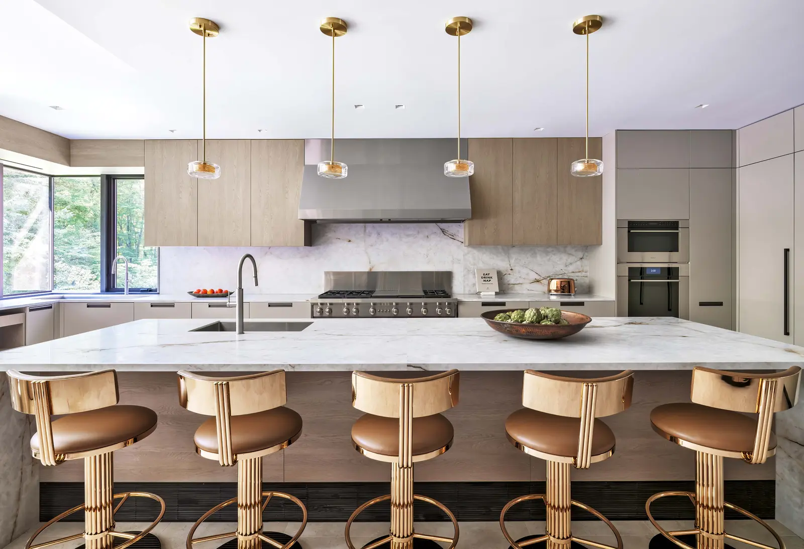 Kitchen island with brass pendant lights and curved counter stools