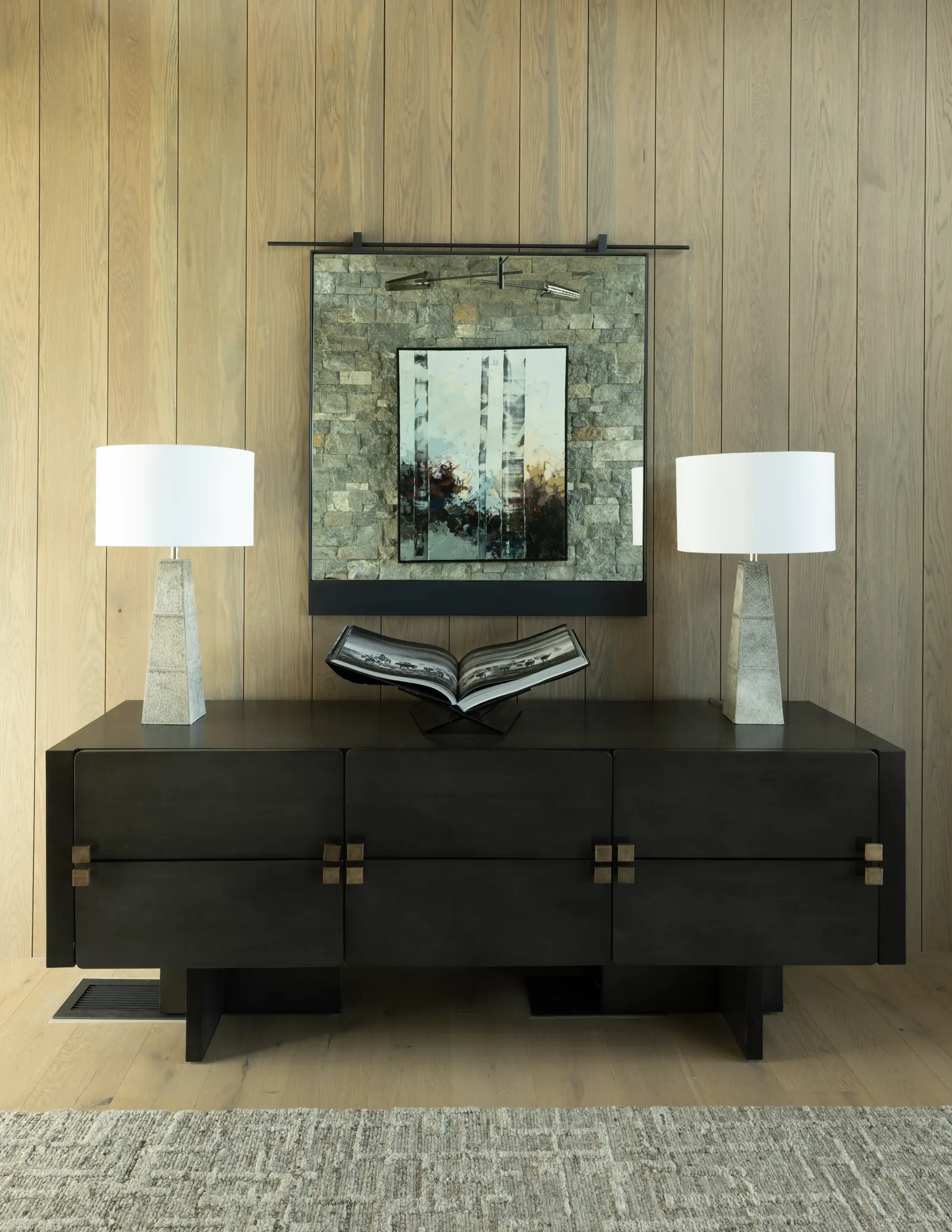 A black console beneath a framed landscape on a timber wall