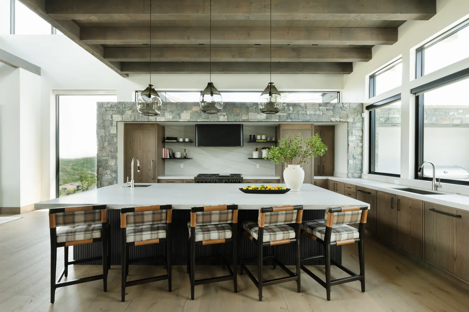 Kitchen with a long stone island, plaid counter stools and mountain views